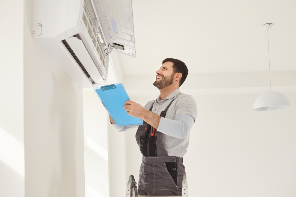 Happy worker handyman man checking, installing attaching wall air conditioning unit, AC repair, room temperature control, adjust optimal device performance, professional technician providing climate