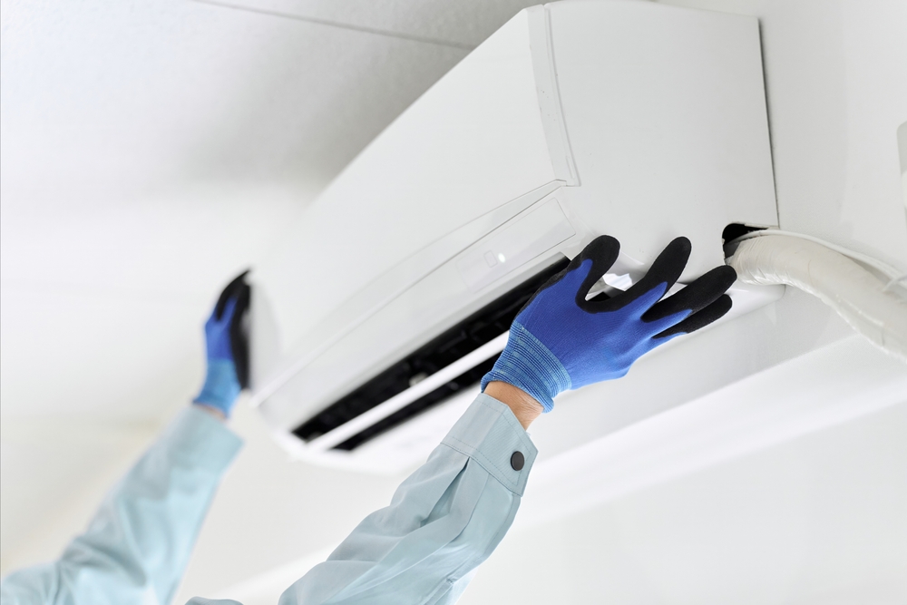 Asian worker inspecting air conditioner